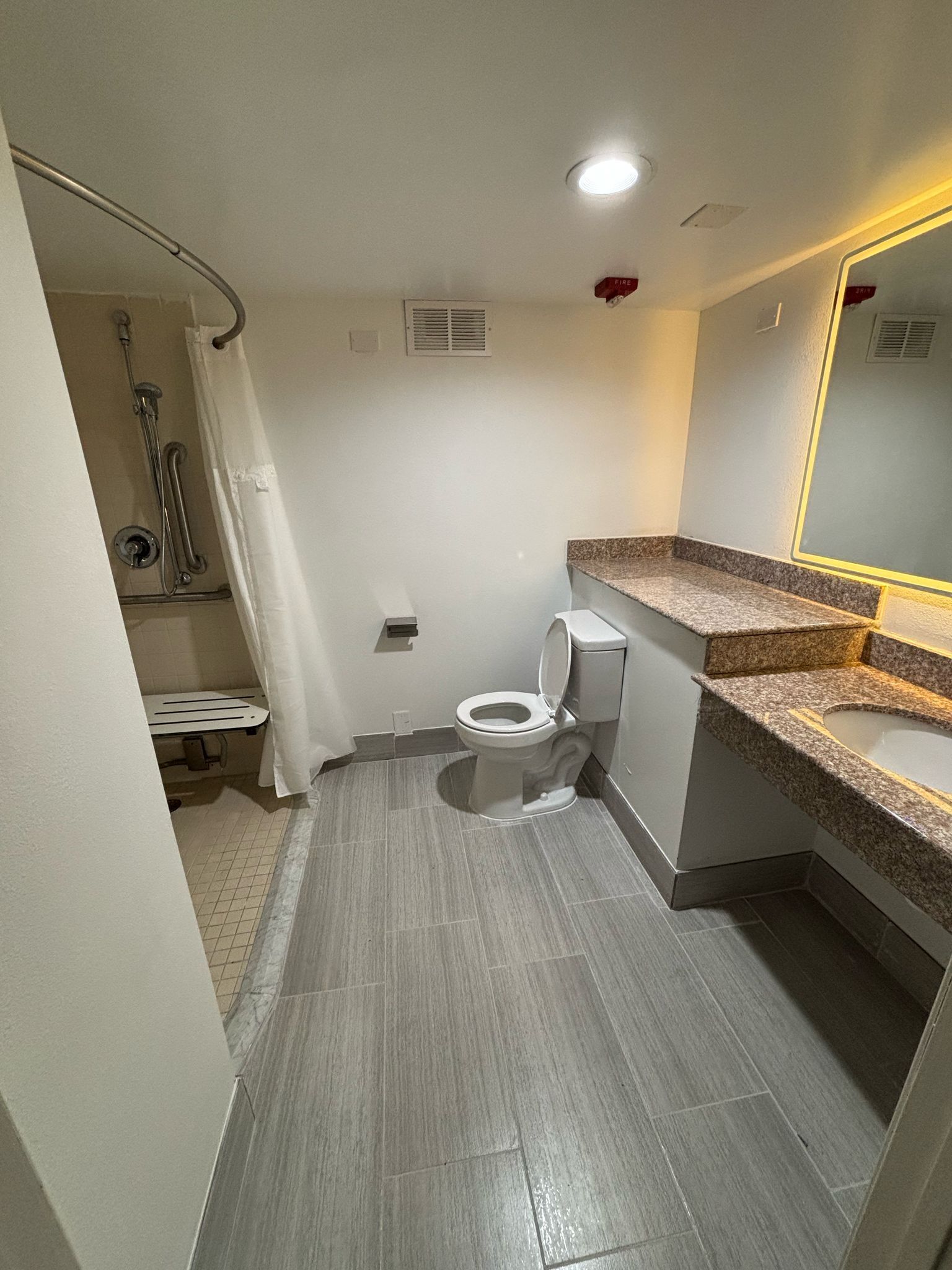 Un bagno con il water, doccia e un lavabo con specchio.