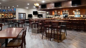 Un restaurante amplio con varias mesas y sillas, una zona de bar y una cocina visible al fondo.