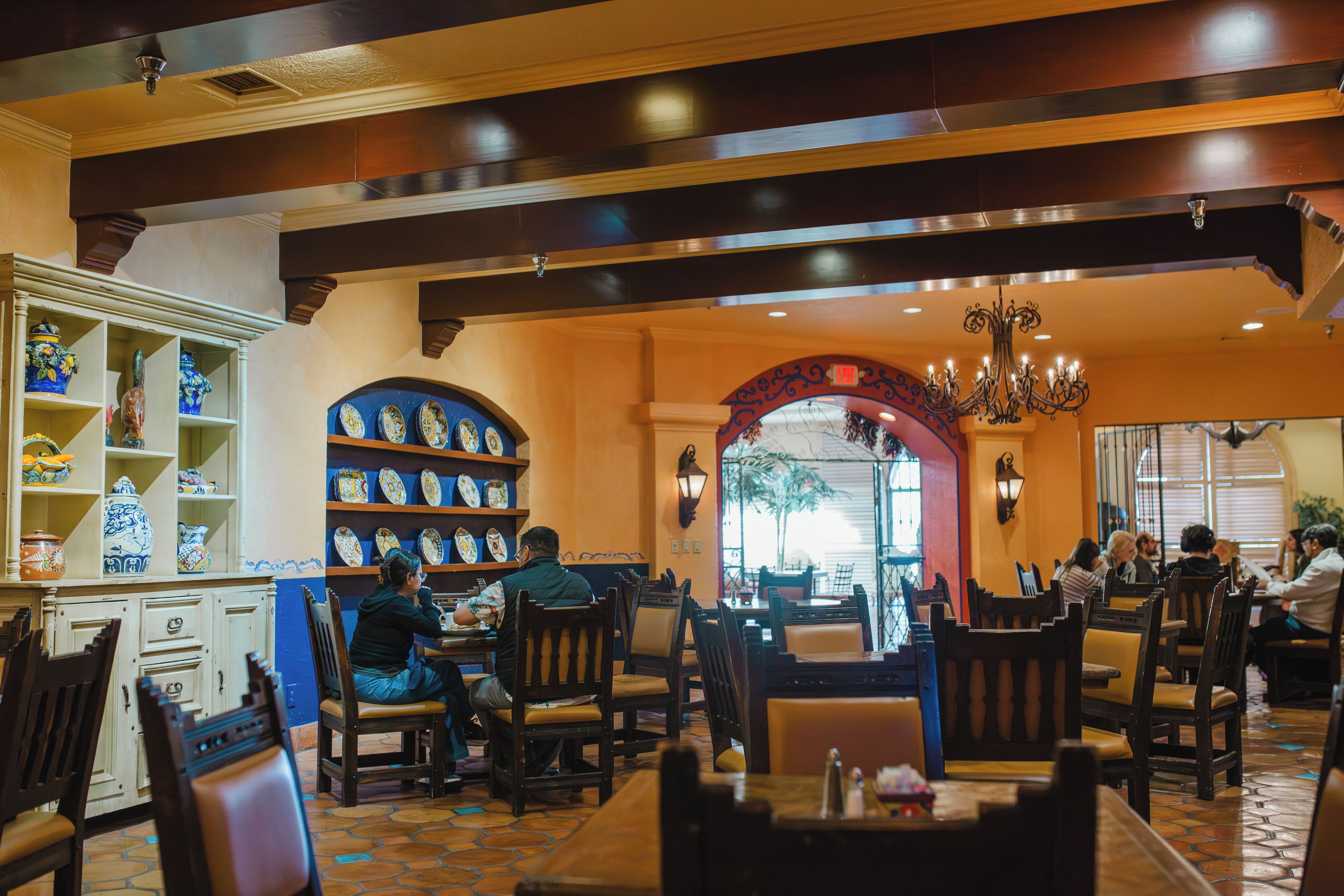 A restaurant interior with high ceilings, a central archway, and a variety of seating arrangements.