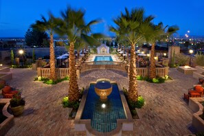 A pool area with a fountain, palm trees, and outdoor seating.
