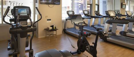 A gym with cardio machines, a treadmill, and a mirror wall.