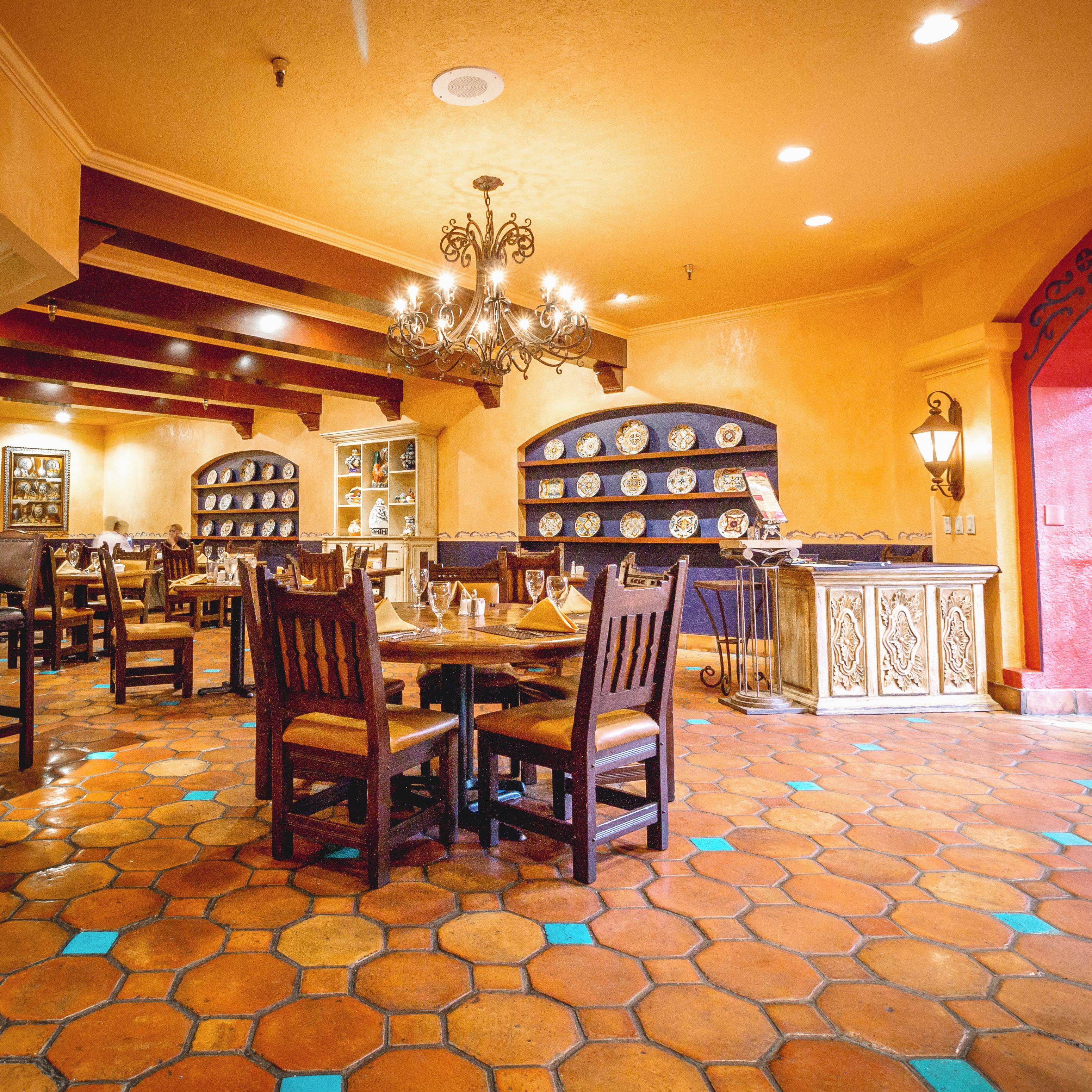 Un interior de restaurante con suelo de patrón hexagonal, mesas y sillas de madera.