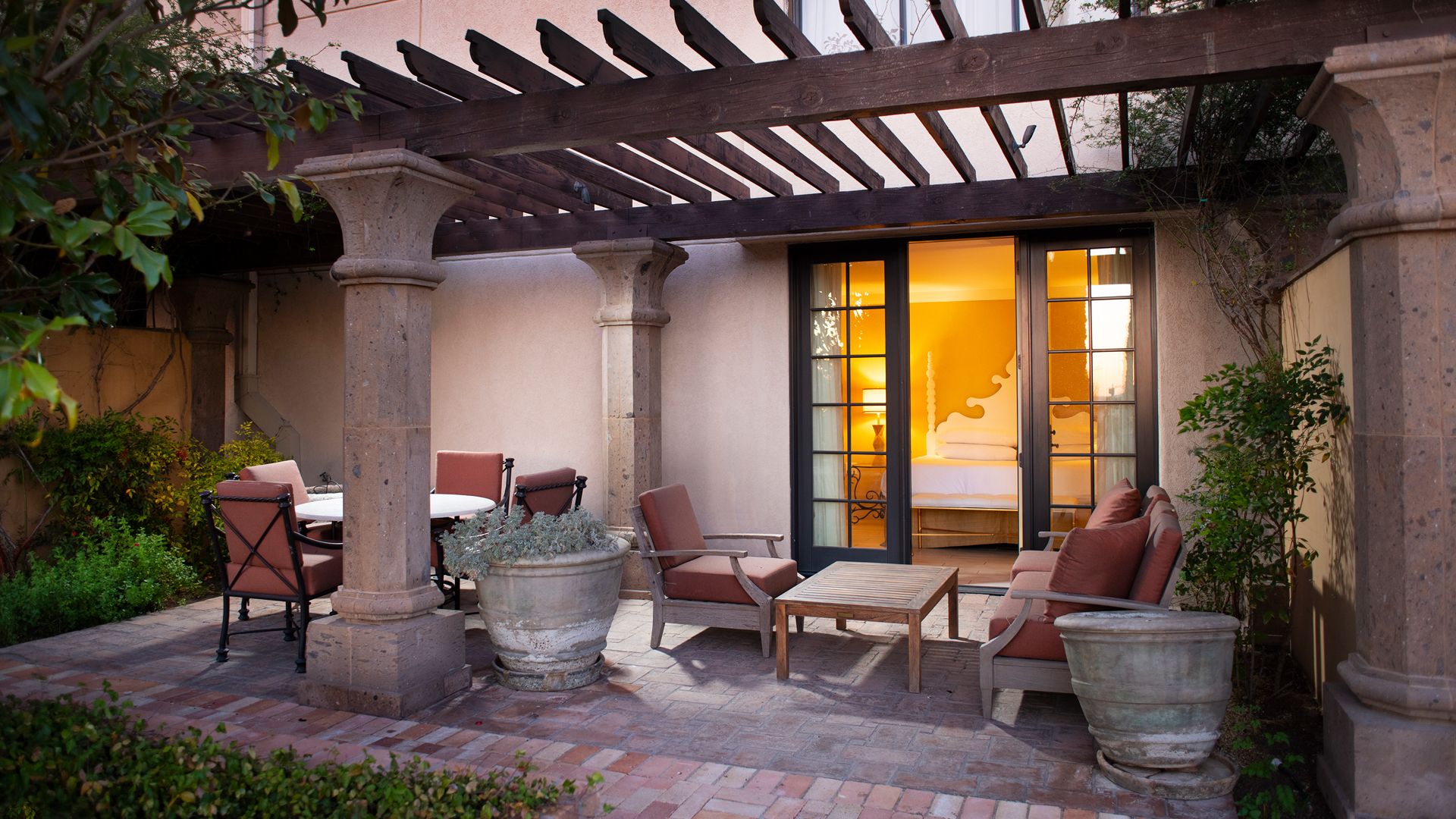A covered outdoor seating area with stone pillars, a table, and chairs.