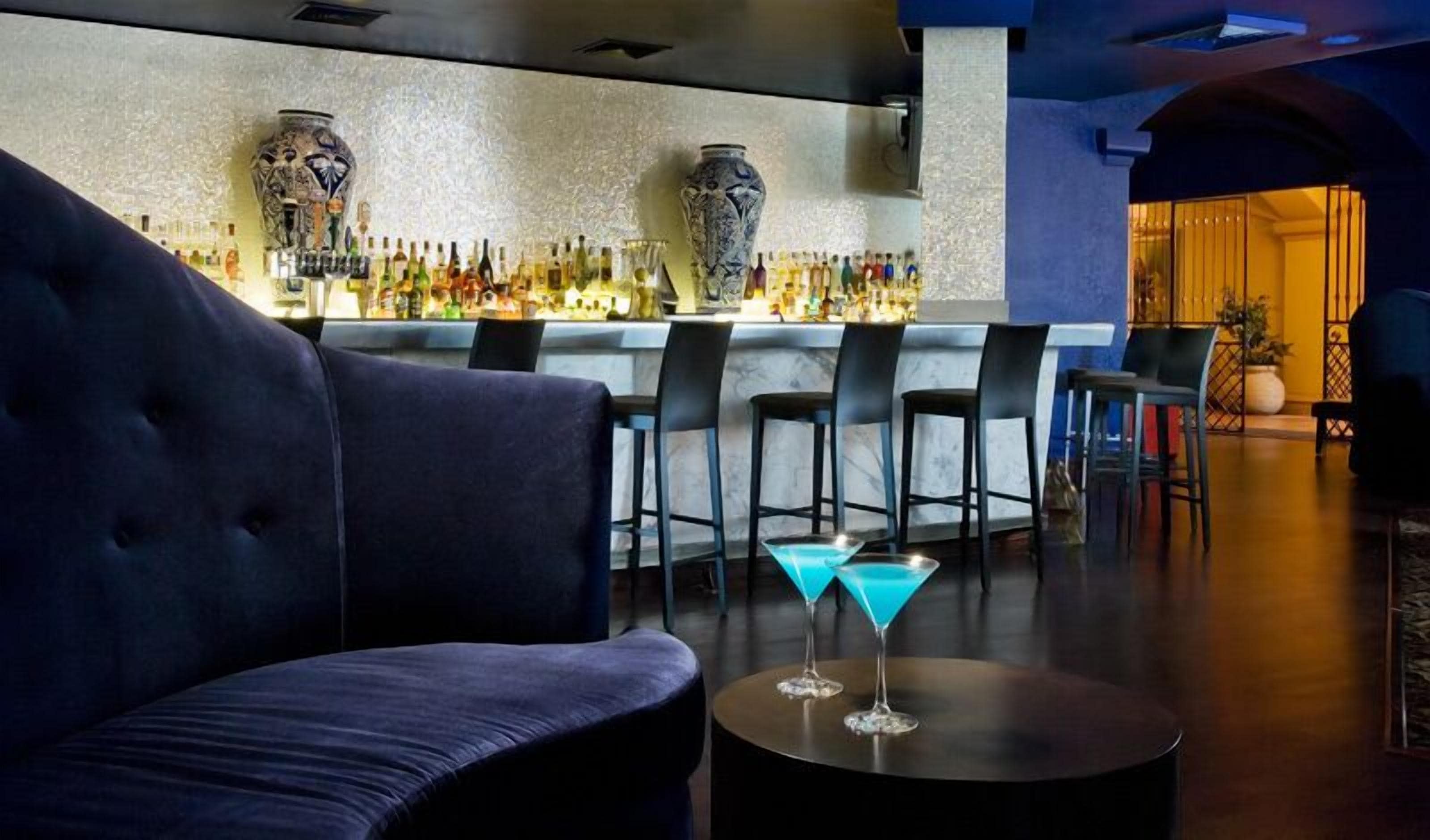 Zona de bar con un sofá, taburetes y una copa de martini sobre una mesa.