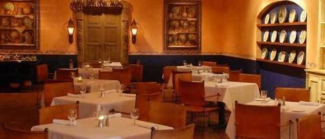 A restaurant interior with round tables, chairs, and a chandelier.