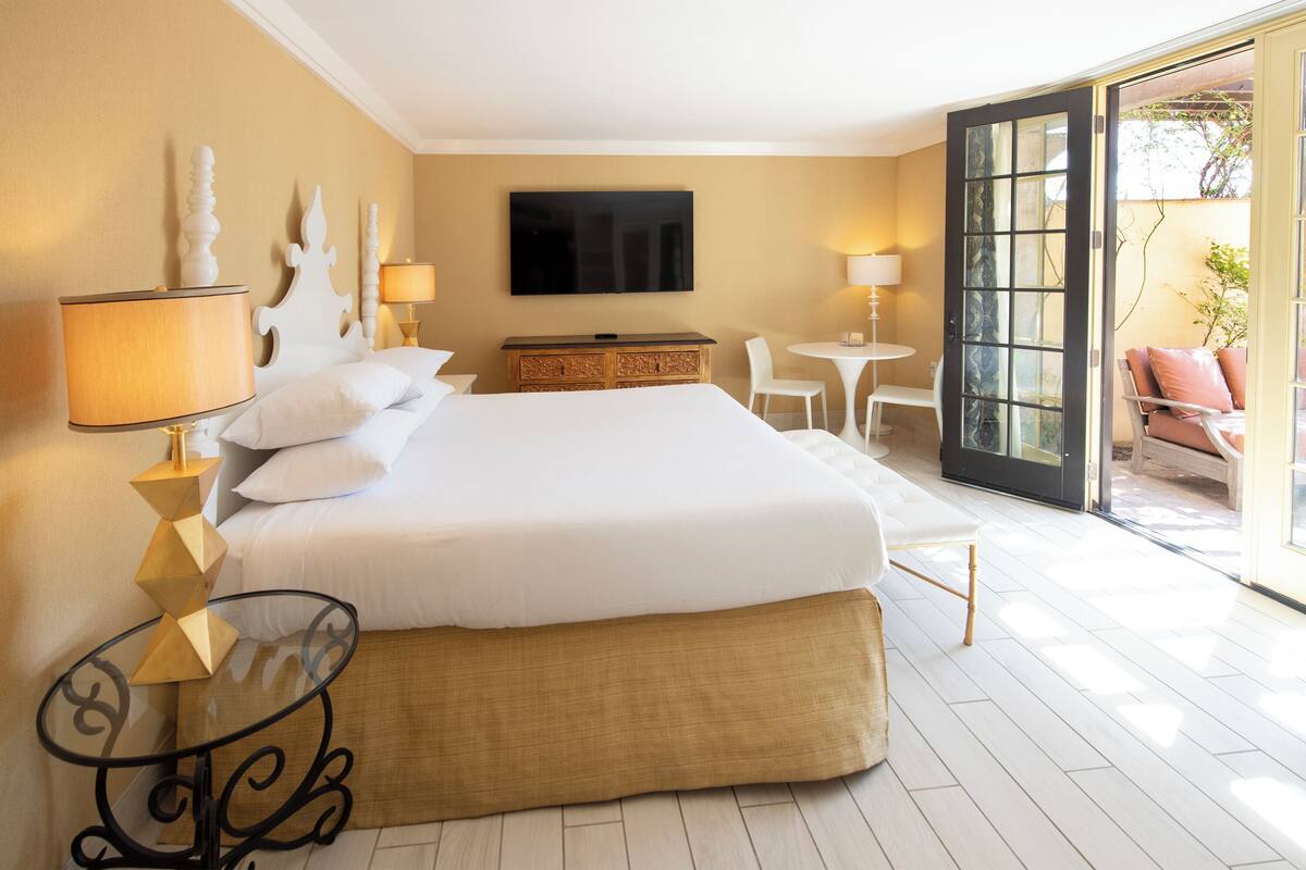 A hotel room with a large bed, a television, a dining table, and a chair.
