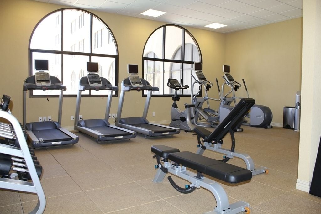 Un gimnasio con cintas de correr, elípticas y una prensa de banca.