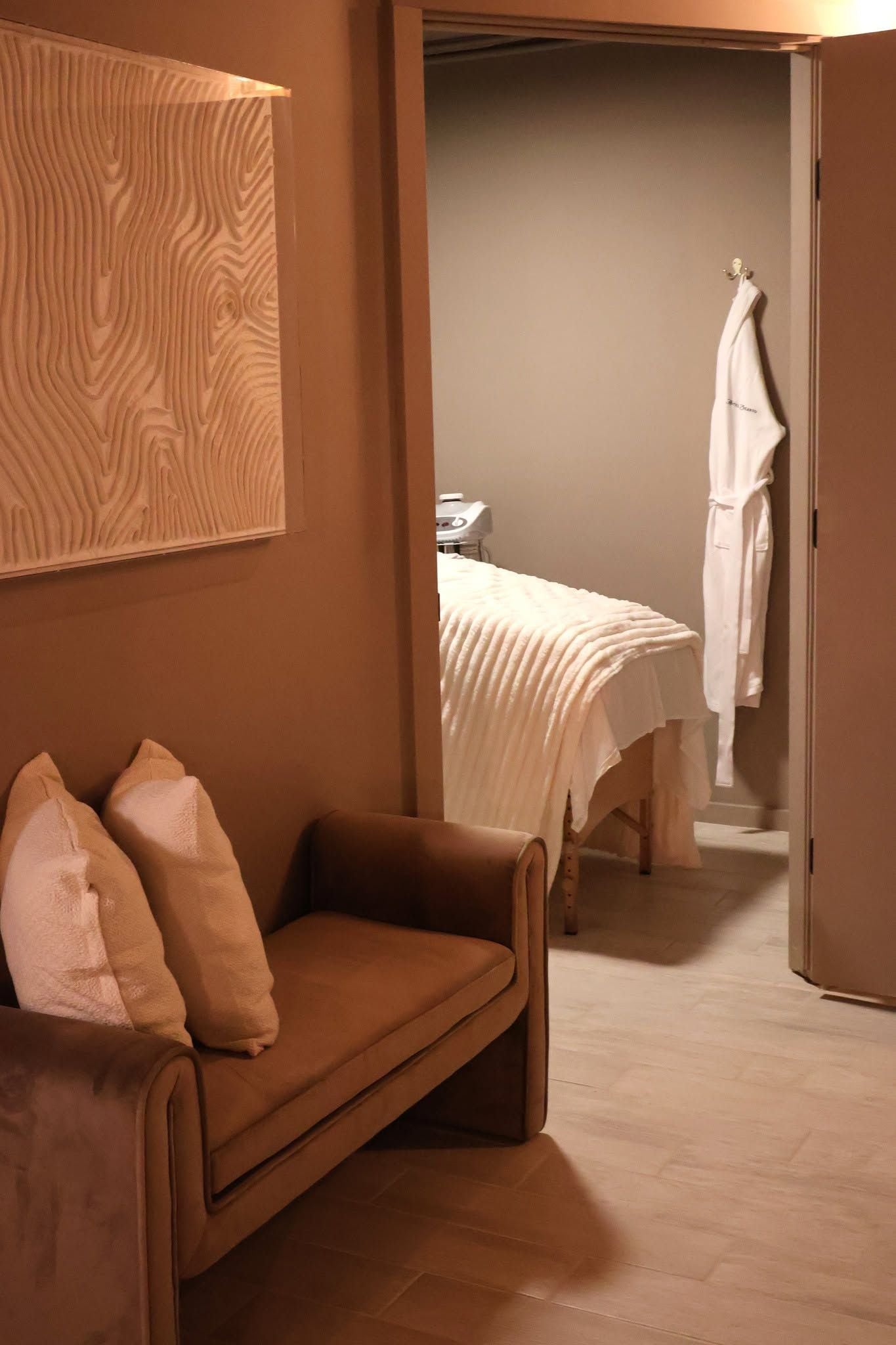 A room with a sofa, a bed, and a wall-mounted artwork.