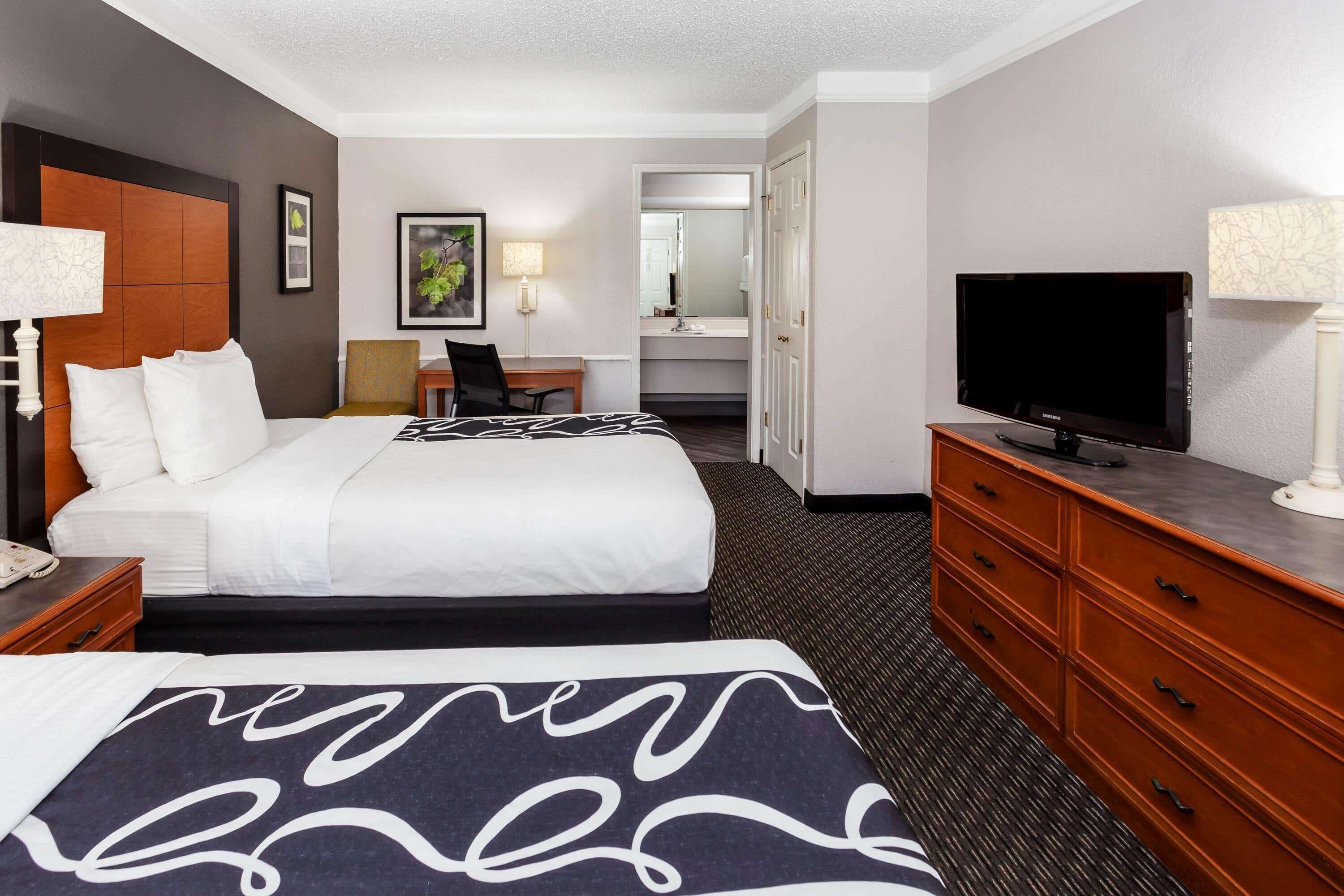 A hotel room with a large bed, a television, a desk, and a dresser.
