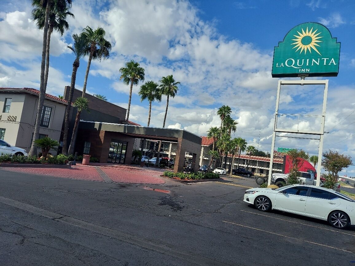 L’entrée d’un hôtel, avec une enseigne indiquant « La Quinta Inn » et des palmiers en arrière-plan.