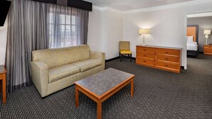 A hotel room with a sofa, a small table, a chair, a dresser, and a bed. - La Quinta Inn by Wyndham Laredo I-35 (Laredo)