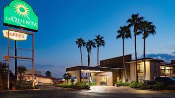 Un hôtel avec une enseigne bien visible indiquant « La Quinta Inn » et un restaurant Tenny's situé à proximité.