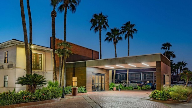 A modern hotel with a covered entrance, palm trees, and a paved driveway. - La Quinta Inn by Wyndham Laredo I-35 (Laredo)