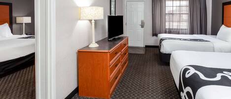 Ein Hotelzimmer mit zwei Betten, einem Fernseher, einem Schminktisch und einer Tür.