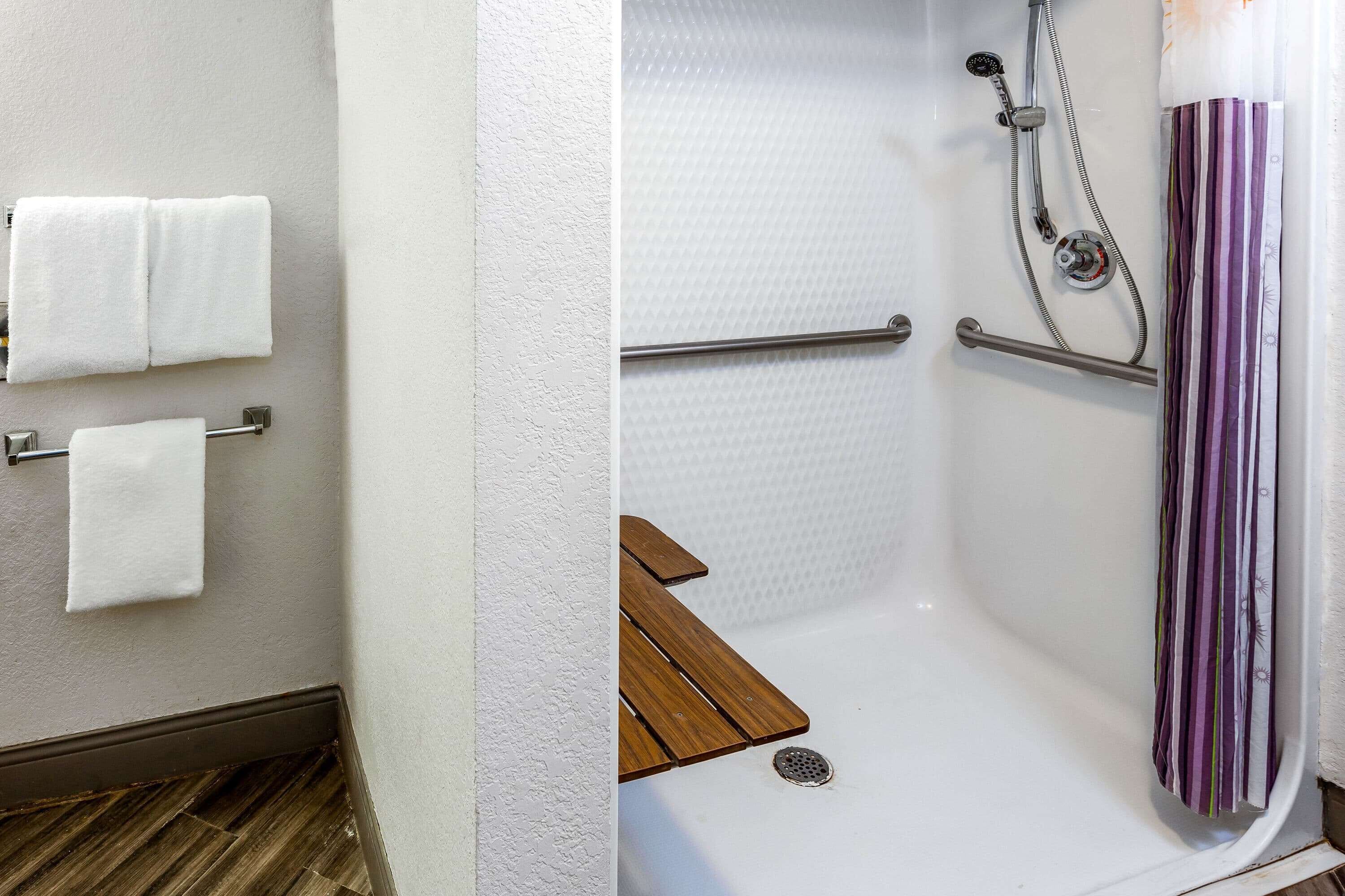 Un baño con ducha, toallero y banco de madera.