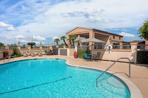 Una piscina al aire libre, sombrillas, sillones reclinables de piscina