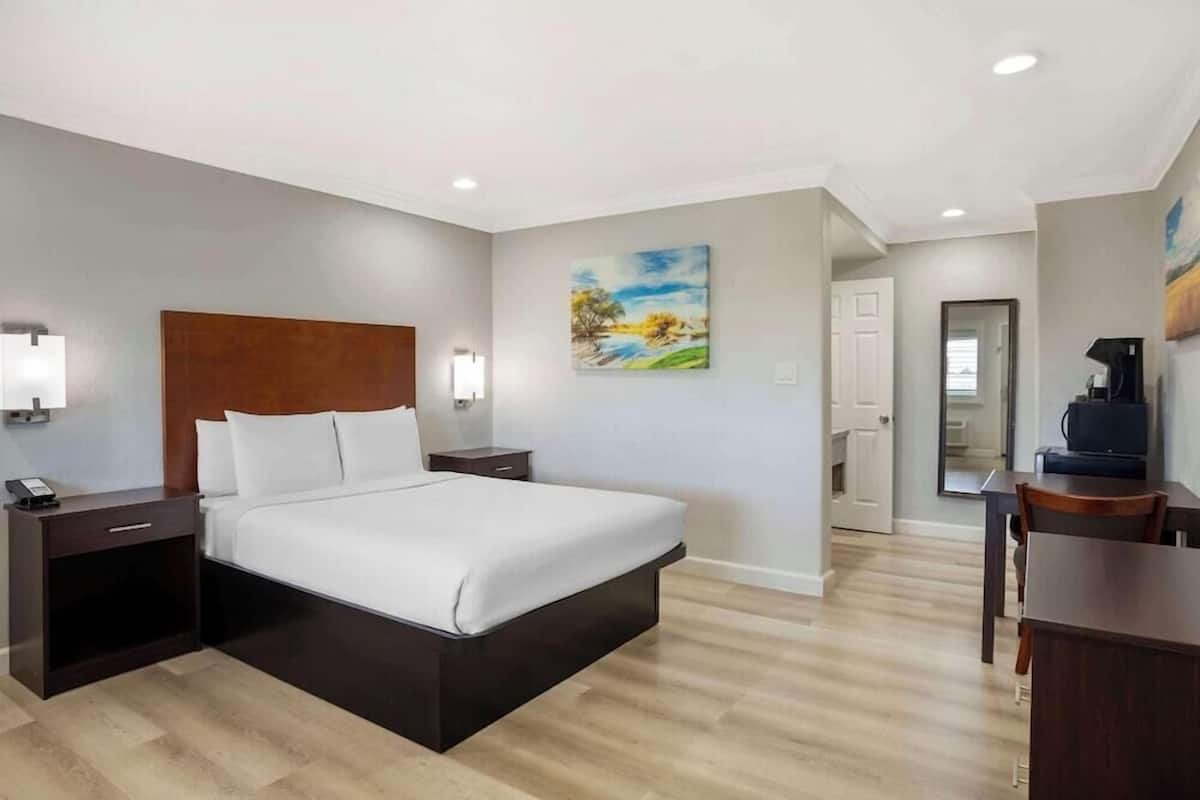 A modern hotel room with a large bed, bedside tables, a desk, and a chair.