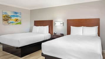 Une chambre d’hôtel avec deux lits, une table de chevet, un téléphone fixé au mur et un tableau.