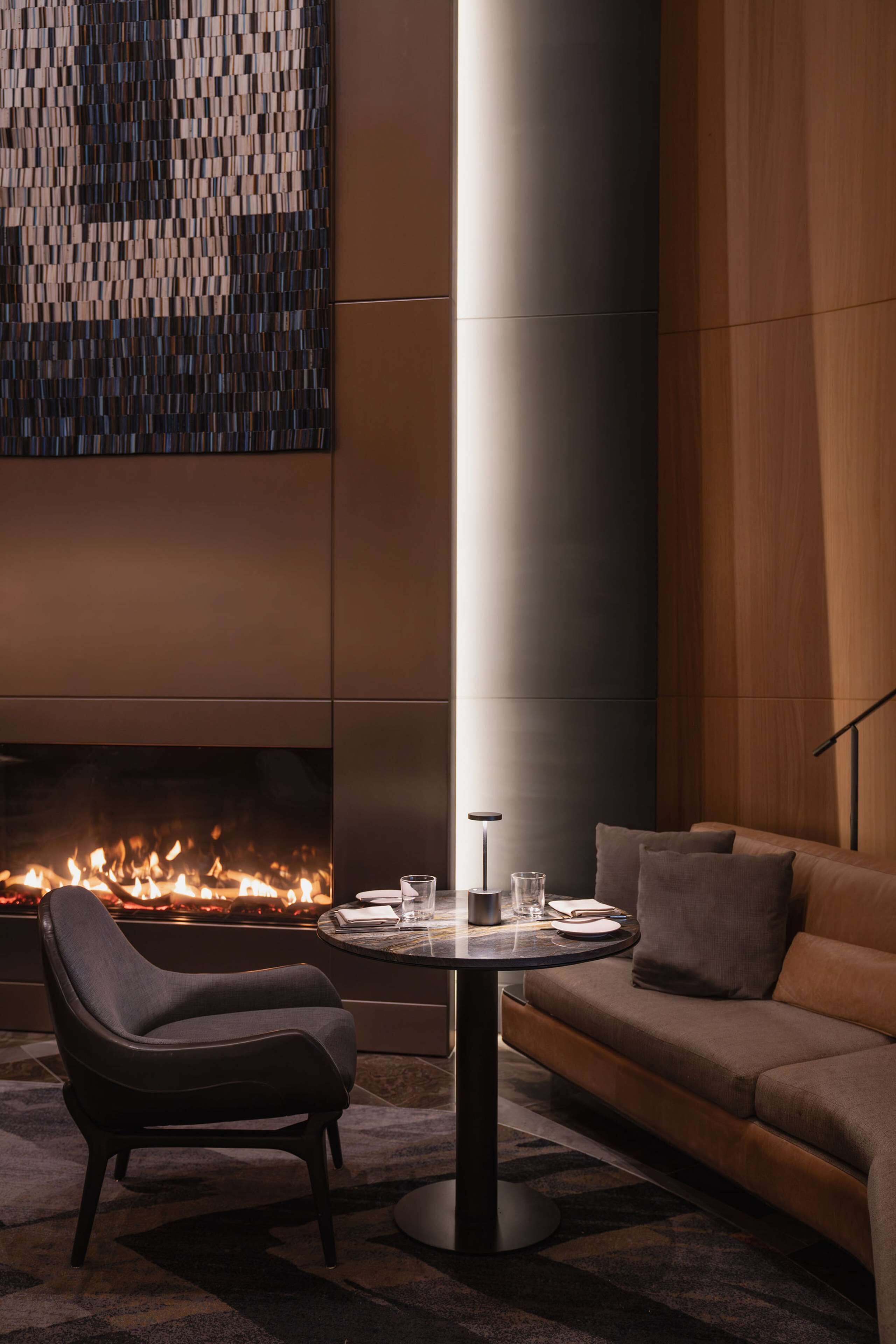 Una sala de estar moderna con chimenea, una mesa de centro redonda, un sofá y un sillón.