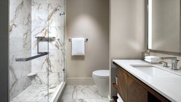 A modern bathroom with a glass-enclosed shower, a white toilet, and a wooden vanity with a sink.