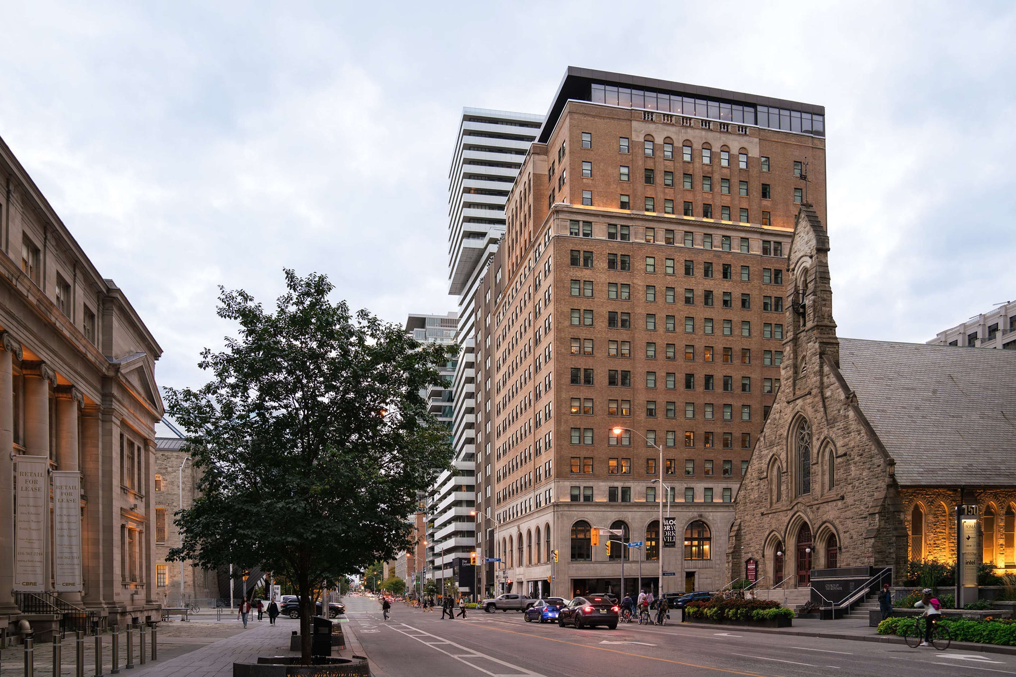 A multi-story building with a mix of modern and traditional architecture, featuring a prominent tower and a church-like structure with arched windows.