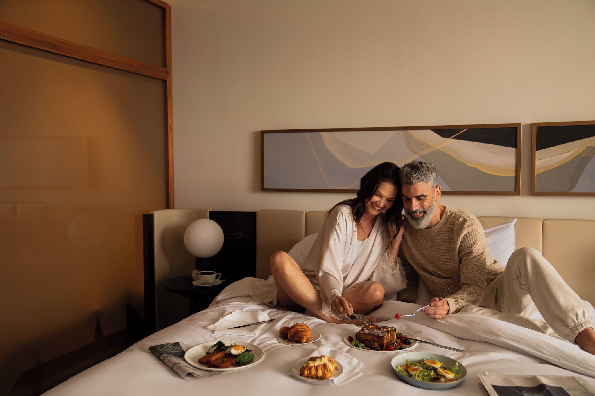 Une chambre d’hôtel avec un lit, un coin petit-déjeuner et des œuvres d’art abstraites accrochées au mur.