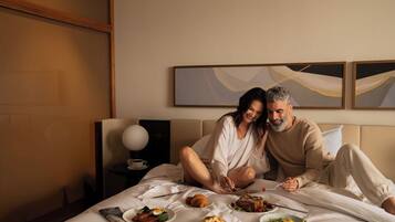 Een hotelkamer met een bed, ontbijtvoorzieningen en abstracte kunst aan de muur.