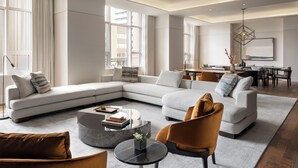 Una sala de estar moderna con un sofá modular, una mesa de centro redonda y un comedor con mesa y sillas.