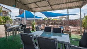 An outdoor patio with a covered seating area, a pool, and a fenced enclosure. - Albury Classic Motor Inn (Lavington)