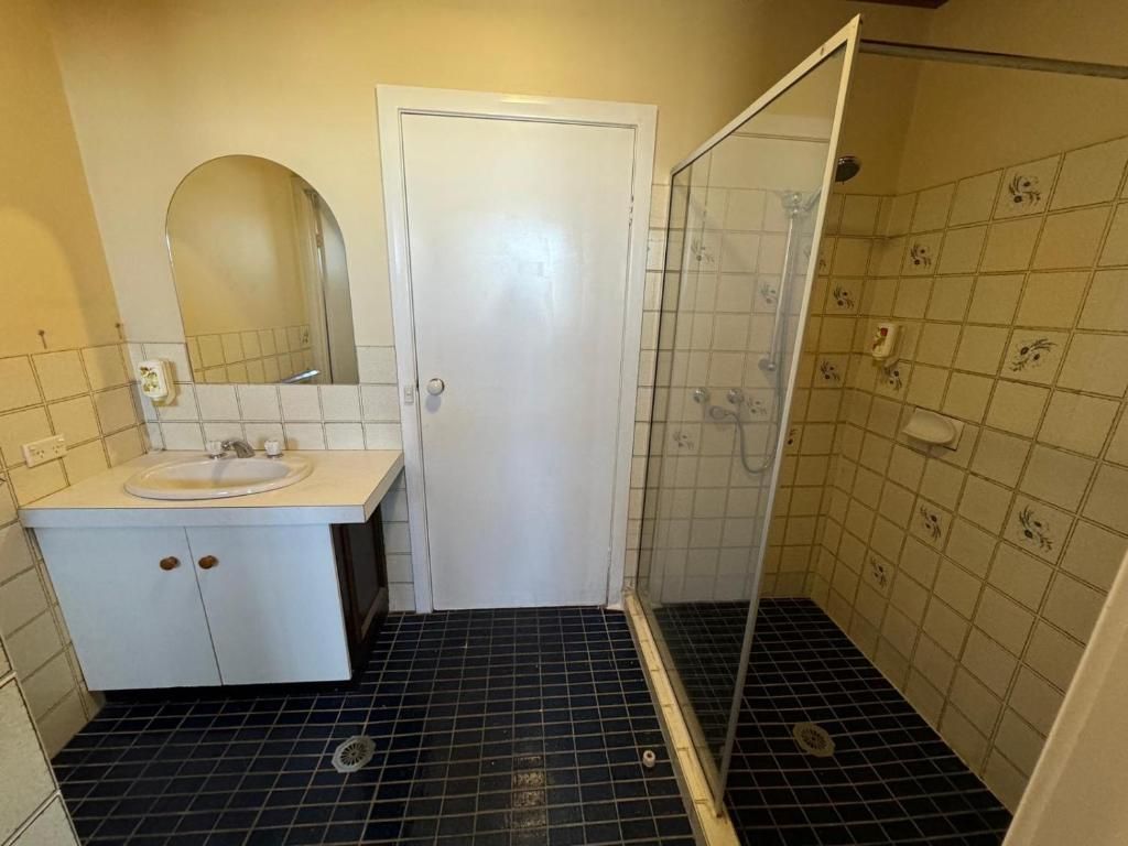 A bathroom with a white sink, mirror, and a shower with a glass door.