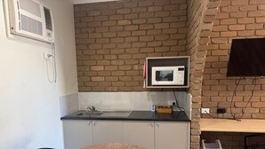 A compact kitchen with a microwave, sink, and a small dining table. - Albury Classic Motor Inn (Lavington)
