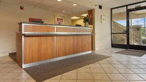 A reception desk with a wooden finish, a tiled floor, and a glass door leading outside. - Red Roof Inn Dayton - Fairborn/ Nutter Center (Fairborn)