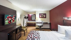 A hotel room with a bed, a desk, a chair, a television, a bathroom, and a painting on the wall. - Red Roof Inn Dayton - Fairborn/ Nutter Center (Fairborn)