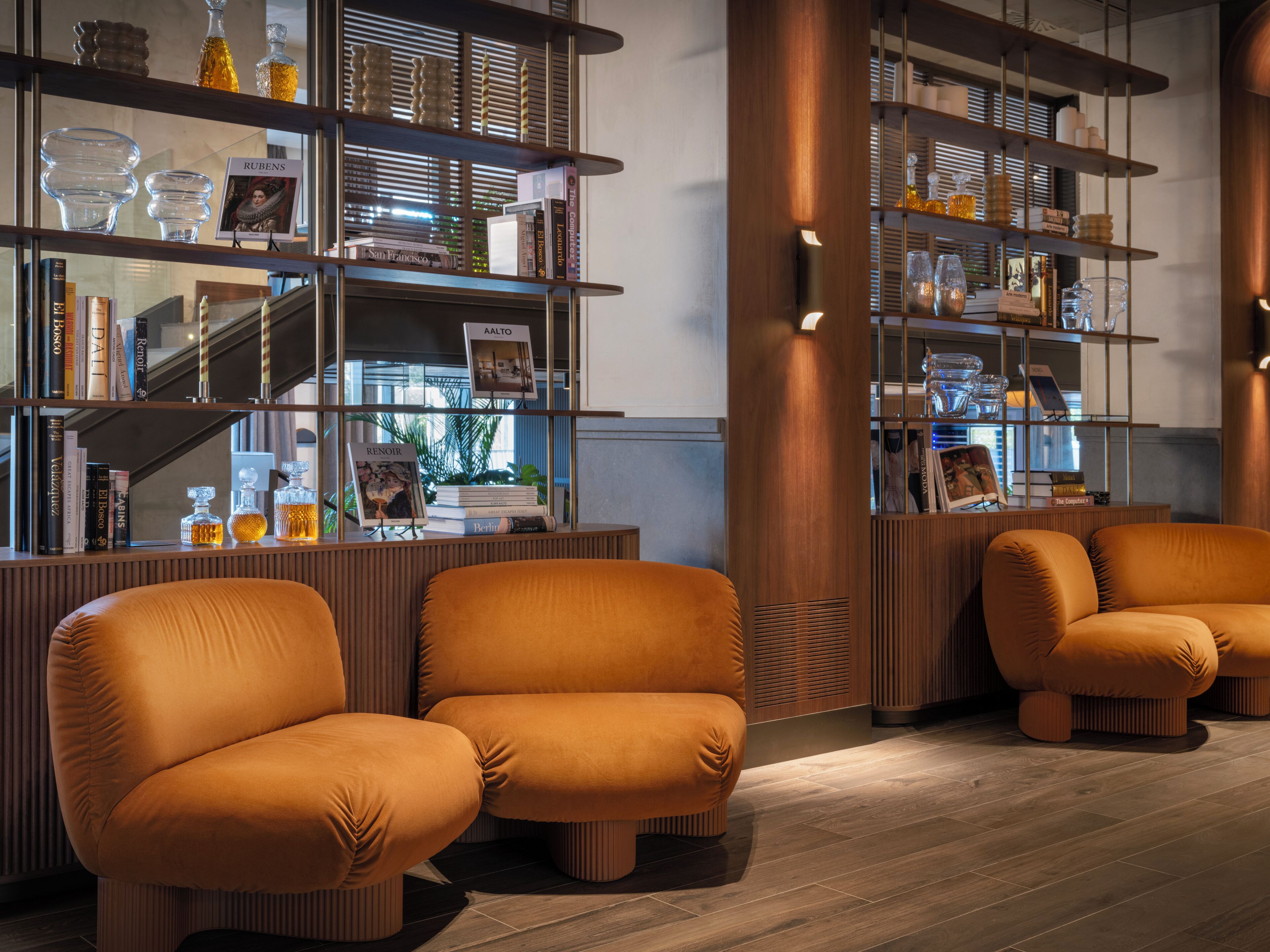 A modern interior with wooden bookshelves, leather armchairs, and a wooden floor.