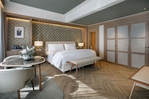 Ein modernes Hotelzimmer mit einem großen Bett, einem kleinen runden Tisch, einer Bank und einem Sofa.