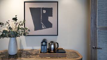 Una habitación con un mapa enmarcado en la pared, un florero con flores y una bandeja con cafetera y tetera.