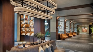 Eine moderne Lobby mit einer gebogenen Couch, Bücherregalen und einer Treppe.