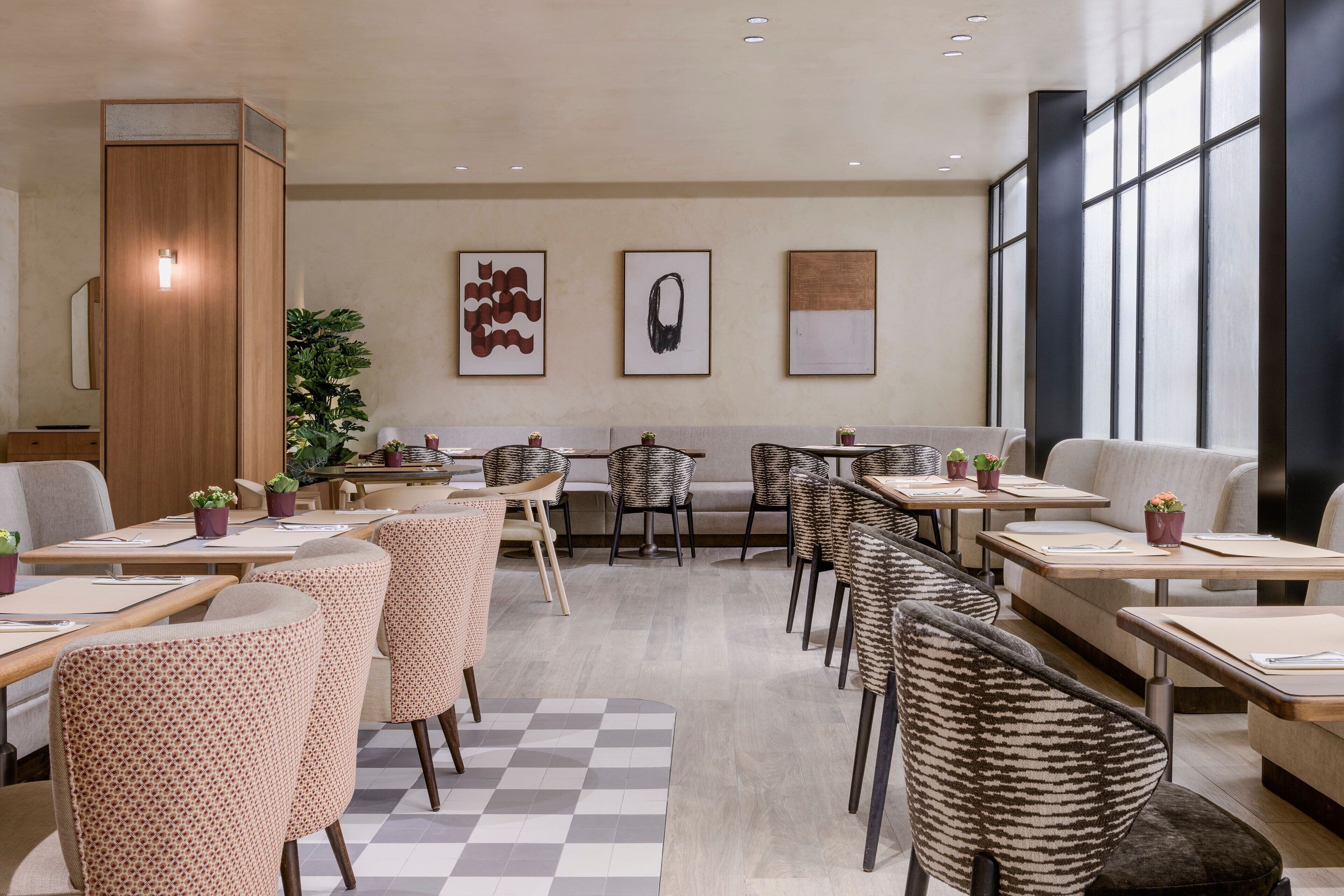 A modern dining area with a mix of seating options, including tables and chairs, and a large window providing natural light.
