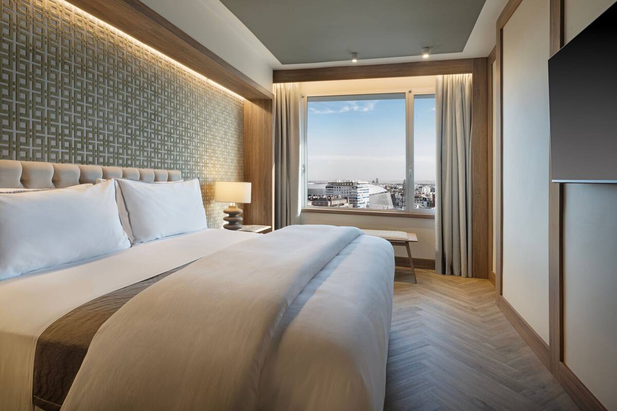 Une chambre d’hôtel avec un grand lit, une vue sur la ville et un mur décoré de motifs.