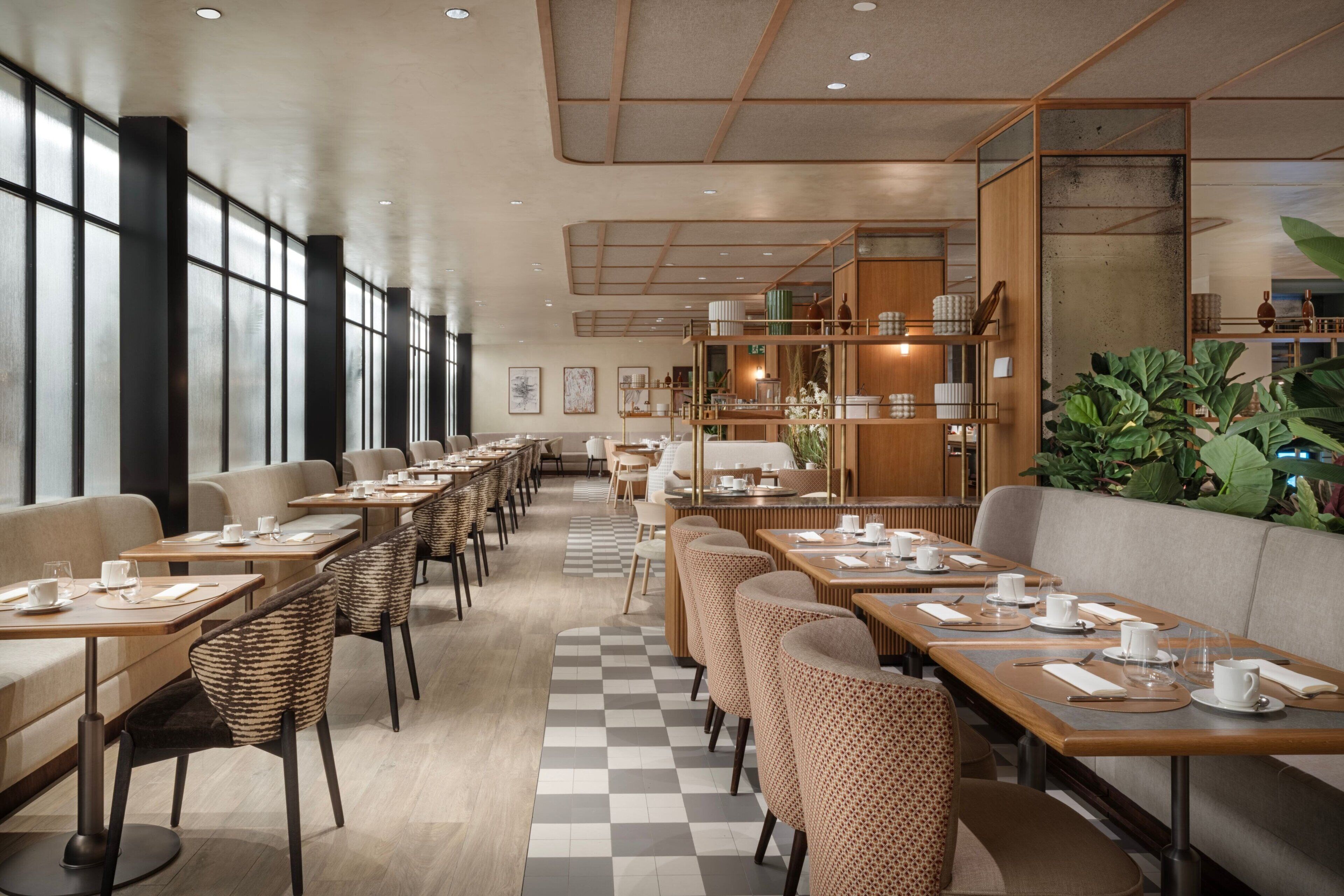 A modern restaurant with long tables, cushioned seating, and a checkered floor.