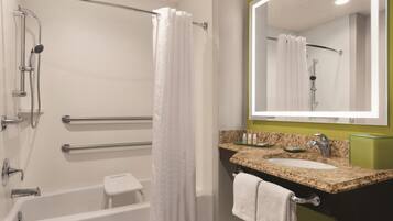 A modern bathroom with a bathtub, shower, and vanity with a sink and mirror.