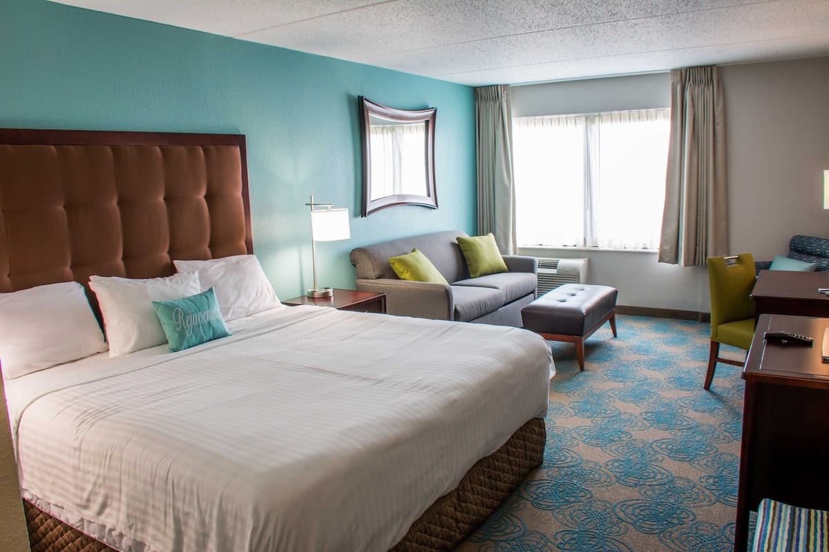 A hotel room with a large bed, a sofa, a desk, and a chair.