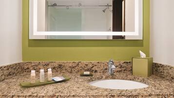 A bathroom with a granite countertop, a sink, and a mirror.