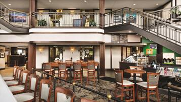 Un vestíbulo de hotel de varios niveles con una zona de comedor, una Starbucks y una escalera.