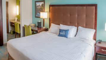 Een hotelkamer met een groot bed, een bureau met telefoon, een stoel en een lamp.