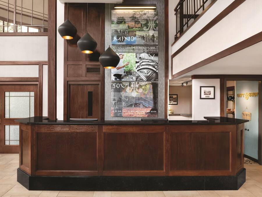 A reception desk with a wooden finish and black countertop, three pendant lights, and a glass display case with a poster.