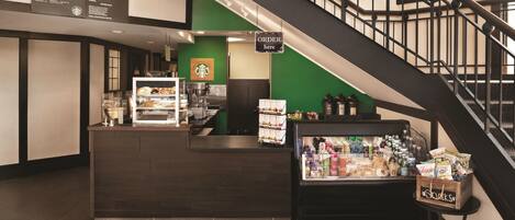 Mostrador de Starbucks con un menú, una máquina de café y una vitrina refrigerada de aperitivos.