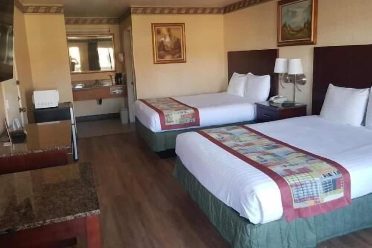 Quarto de hotel com duas camas, uma mesa, um espelho e um quadro na parede.