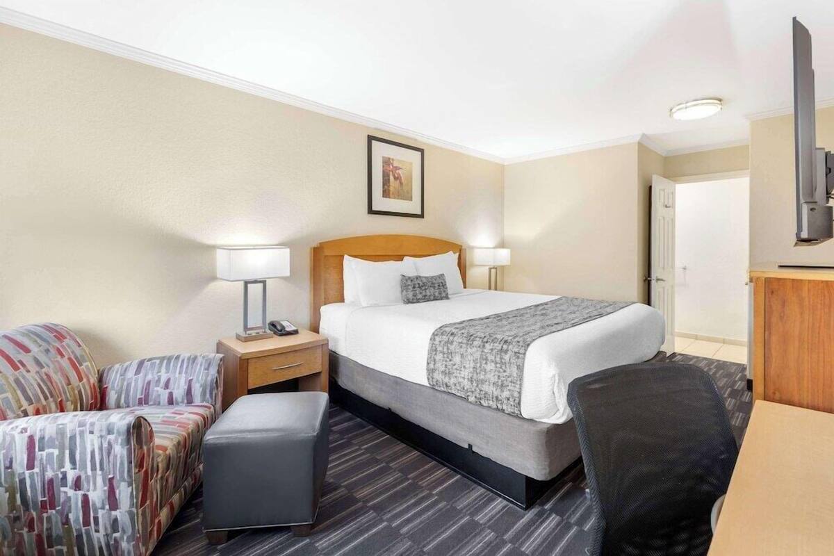 Une chambre d’hôtel équipée d’un lit, d’un bureau, d’une chaise, d’un canapé et d’une télévision.