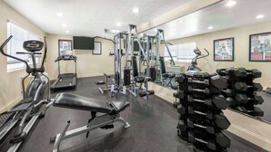 Une salle de sport équipée de tapis de course, d’appareils de musculation et de poids libres.